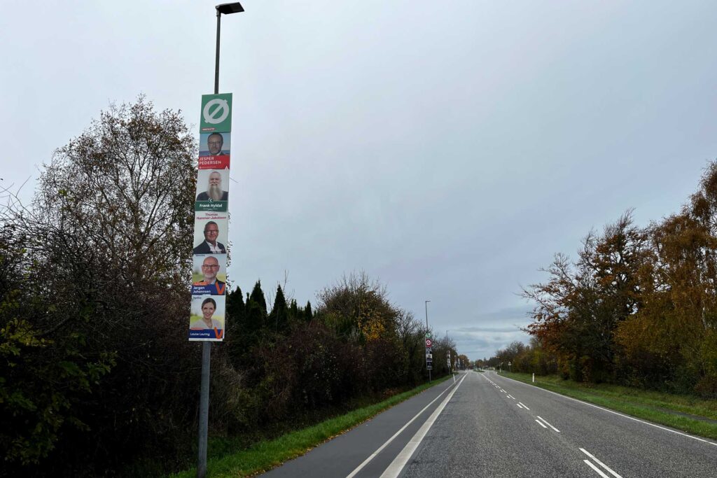 Valgplakater der hænger i lygtepæle langs en vej