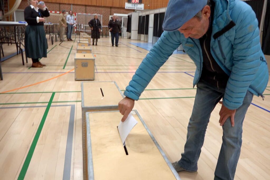 En mand lægger sin stemmeseddel i en stemmboks
